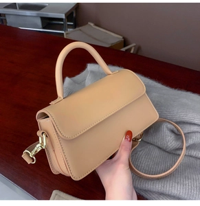 Detail of beige leather crossbody bag with rounded top handle and adjustable strap