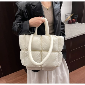 Detailed view of large quilted white puffy tote bag with thick handles and padded texture