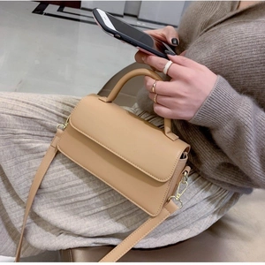 Detail of beige square handbag with round handle and detachable shoulder strap