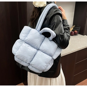 Detailed close-up of light blue quilted puffer tote bag with premium padding texture