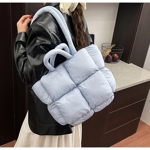 Macro shot of light blue quilted puffer bag with plush padded texture and chunky strap
