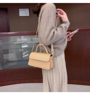 Detailed side view of apricot leather crossbody bag with rounded handle and thin strap