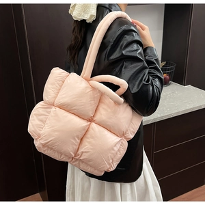 Pink quilted puffer tote bag shown on model with large rhombus stitching and soft texture
