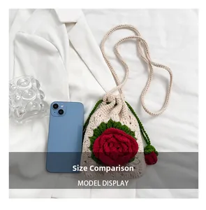 Size comparison of a handmade crochet bag with red flower detail next to a smartphone