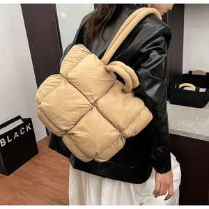 Detail of beige quilted puffer tote bag with puffy woven texture and round top handles