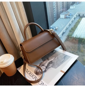 Detailed close-up of a vintage brown leather handbag on a table with a magazine
