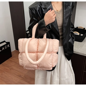Detail of light pink quilted puffer tote bag with soft cylindrical handles and puffy design