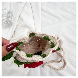 Close-up of handmade crochet drawstring bag with red flower patterns and knitted texture