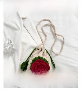 Close-up of handmade crochet drawstring bag featuring 3D red rose and green leaf details