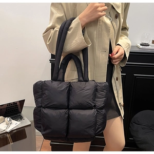Detail of black quilted puffer tote bag showing padded texture and wide handle