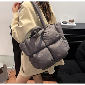 Detail view of large quilted puffer tote bag in charcoal grey with wide shoulder strap