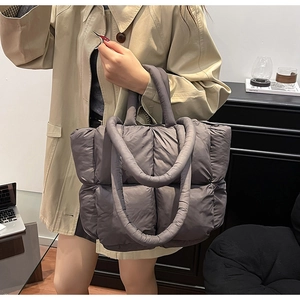 Close-up of dark grey quilted puffer tote bag with handles and a long shoulder strap