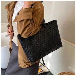 Détail du grand sac cabas noir en cuir tressé avec de fines anses sur le modèle