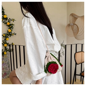 Detailed close-up of handmade crochet bag featuring 3D red rose flower and green leaves