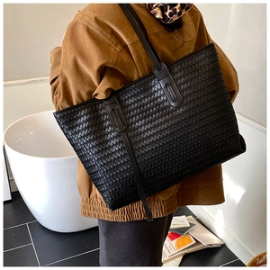 Détail d'un grand sac cabas noir tressé avec motif Intrecciato porté à l'épaule