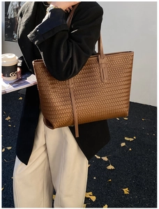 Détail du grand sac cabas tressé marron avec texture croisée et fine bandoulière élégante