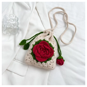 Detail of handmade crochet drawstring bag featuring red 3D rose and green leaf patterns