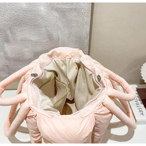 Inside view of pink quilted tote bag showing beige lining and interior zipper pocket
