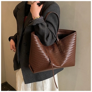 Détail d'un sac cabas en cuir tressé marron foncé avec de longues anses sur mannequin