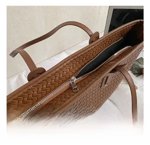 Vue détaillée de la texture tressée marron et de la fermeture éclair en métal du sac