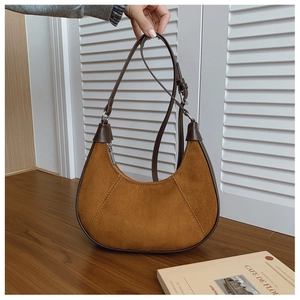 Detail of vintage caramel suede crescent bag with leather trim and silver zipper hardware