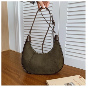 Detailed texture of dark olive green suede crescent bag with brown leather shoulder strap