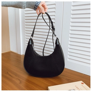 Detail of black crescent shoulder bag with contrast stitching and matte suede finish