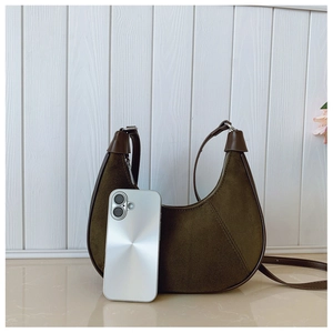 Detail of green suede hobo bag with brown leather trim and metal zipper closure