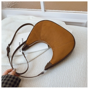 Detailed close-up of brown suede crescent bag with smooth leather trim and silver metal zipper