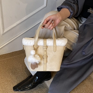 Beige bucket bag with plush white faux fur trim and cute heart charm for winter style