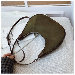 Macro detail of olive green suede fabric texture and smooth leather piping on crescent bag