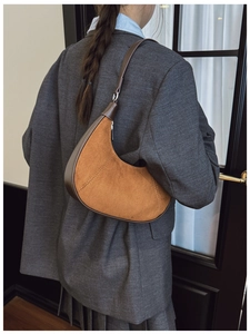 Brown hobo shoulder bag in suede and leather worn by a model in a minimal outfit