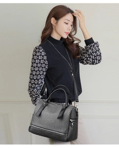 Close-up of woven texture shoulder bag with leather handles and silver zipper details