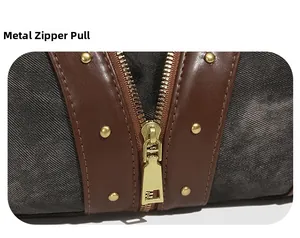Détail de la fermeture éclair dorée et du patchwork en cuir sur le sac en toile gris foncé