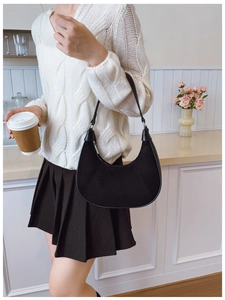 Detail view of a black crescent shoulder bag styled with a minimalist white knit sweater