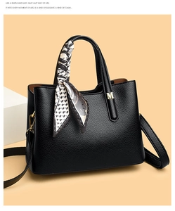 Dettaglio della borsa in pelle martellata nera con logo M dorato e foulard di seta