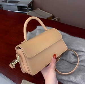 Modern beige rectangular crossbody bag with round handle and gold hardware detail