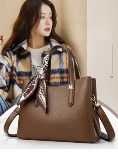 Dettaglio borsa tote marrone in pelle litchi con logo M dorato e foulard in seta sul manico