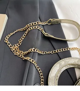 Détails de la bandoulière en chaîne dorée et texture peau de serpent sur le sac