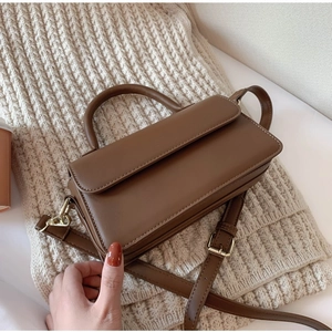 Classic dark brown matte leather handbag with adjustable strap in warm lifestyle setting