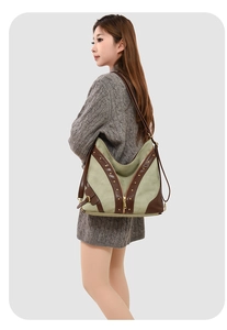Détail du cabas en toile vert sauge avec lanières en cuir marron sur une robe en maille