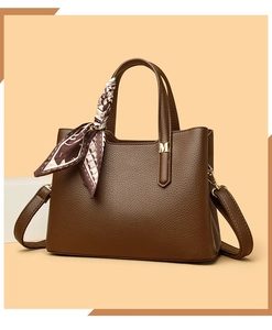 Dettaglio della borsa in pelle marrone con logo M dorato e foulard di seta decorativo