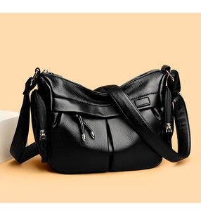Dettaglio borsa a tracolla in pelle nera con tasche con nappe e trama a grana litchi