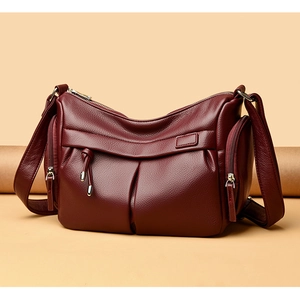 Dettaglio della borsa a tracolla in pelle bordeaux con tasche multiple a zip