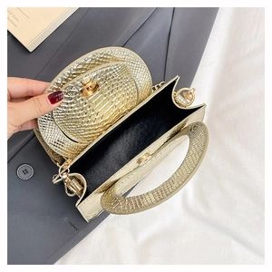 Détail du sac à main doré texture serpent avec poignée métallique et doublure noire