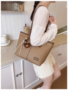 Detail of khaki tote bag with litchi texture leather and cute bear charm pendant