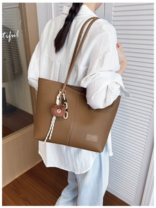 Brown lychee grain leather tote bag with bear charm shown on model in white shirt