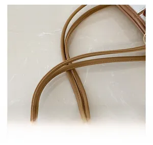 Close-up of brown PU leather tote bag handles with neat stitching on marble background