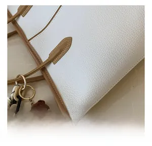 Close-up of white lychee leather texture with brown edges and a cute bear charm