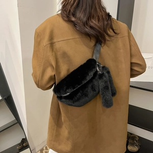 Detail of black faux fur waist bag with silver zipper and matching plush charm